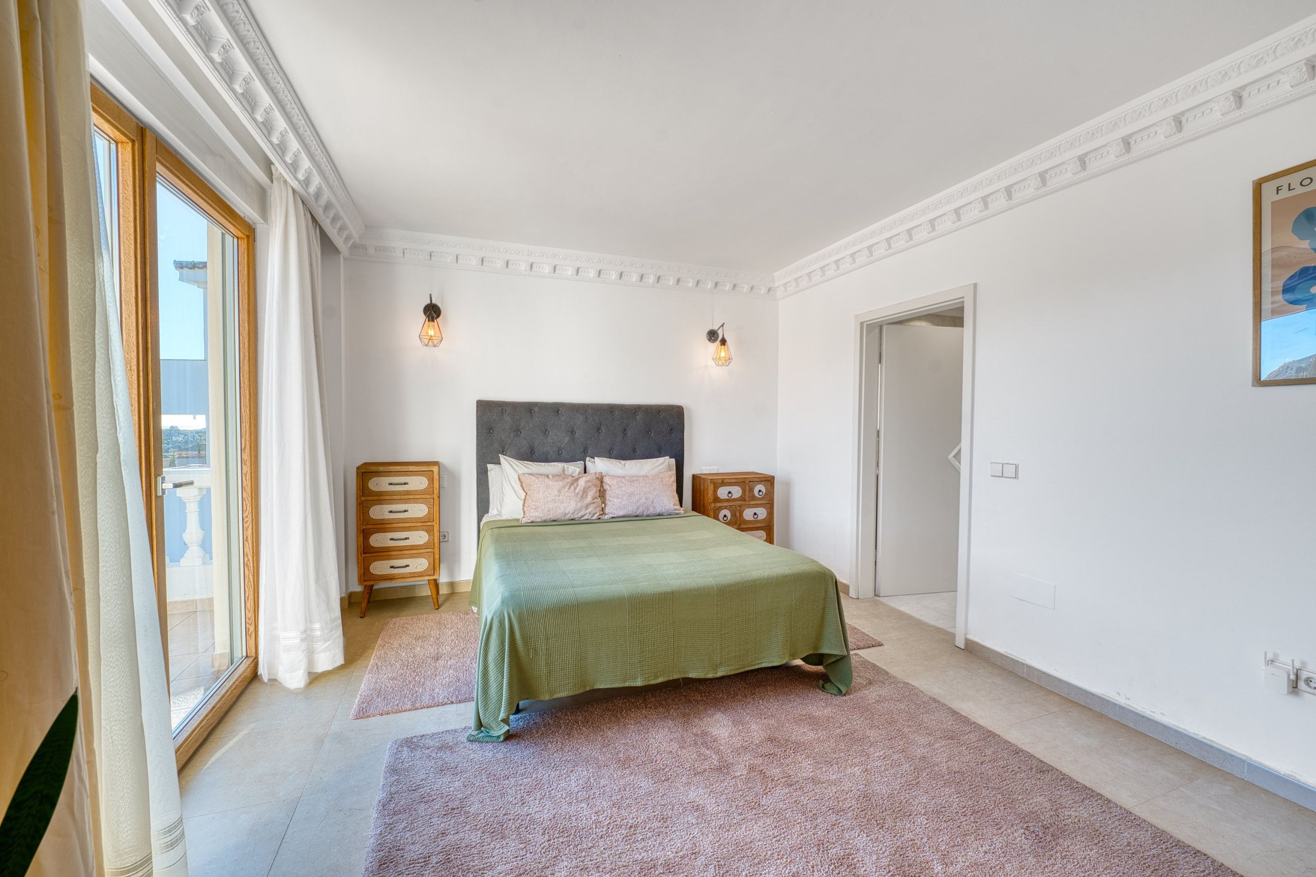 A bedroom with a bed, dresser, and a door leading to another room.