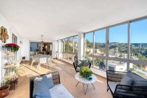 A spacious balcony with a dining area, seating, and plants.