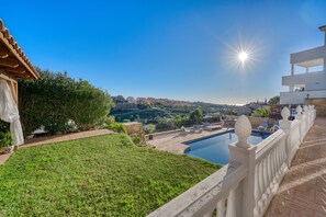 A pool area with a view of a cityscape, a white fence, and a clear sky.