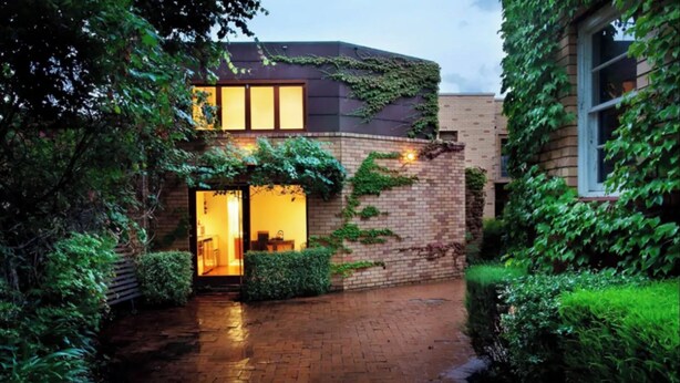 Una casa moderna con facciata in mattoni, ampie finestre e un giardino curato.