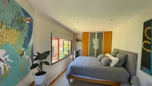 Una camera da letto moderna con un letto, una pianta in vaso, una finestra e un quadro appeso al muro.