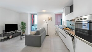 Een moderne woonkamer met een flatscreen televisie, een grijze bank en een bijzettafeltje.