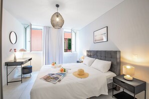 A modern bedroom with a large bed, bedside tables, a desk, and a hanging light fixture. - Corte di Ascona 1 with AC & Wi‑Fi for 4, Ascona, Switzerland (Ascona)