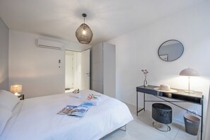 Une chambre d’hôtel moderne, dotée d’un grand lit, d’une table de chevet, d’un bureau et d’un miroir.