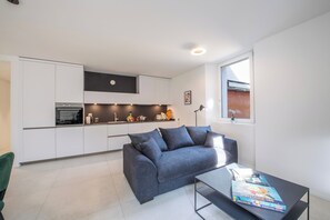A modern kitchen with white cabinets, a built-in oven, and a clock on the wall. - Corte di Ascona 1 with AC & Wi‑Fi for 4, Ascona, Switzerland (Ascona)