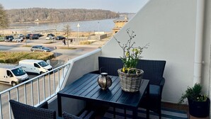 Un balcon agrémenté de meubles en osier, d’une table et d’une plante en pot.