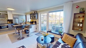 Une cuisine moderne avec un coin repas, un canapé et une vue sur la ville grâce à de grandes fenêtres.