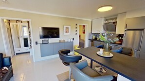 Une cuisine moderne dotée d’un îlot central, de meubles de couleur grise et d’un téléviseur à écran plat fixé au-dessus de l’îlot.