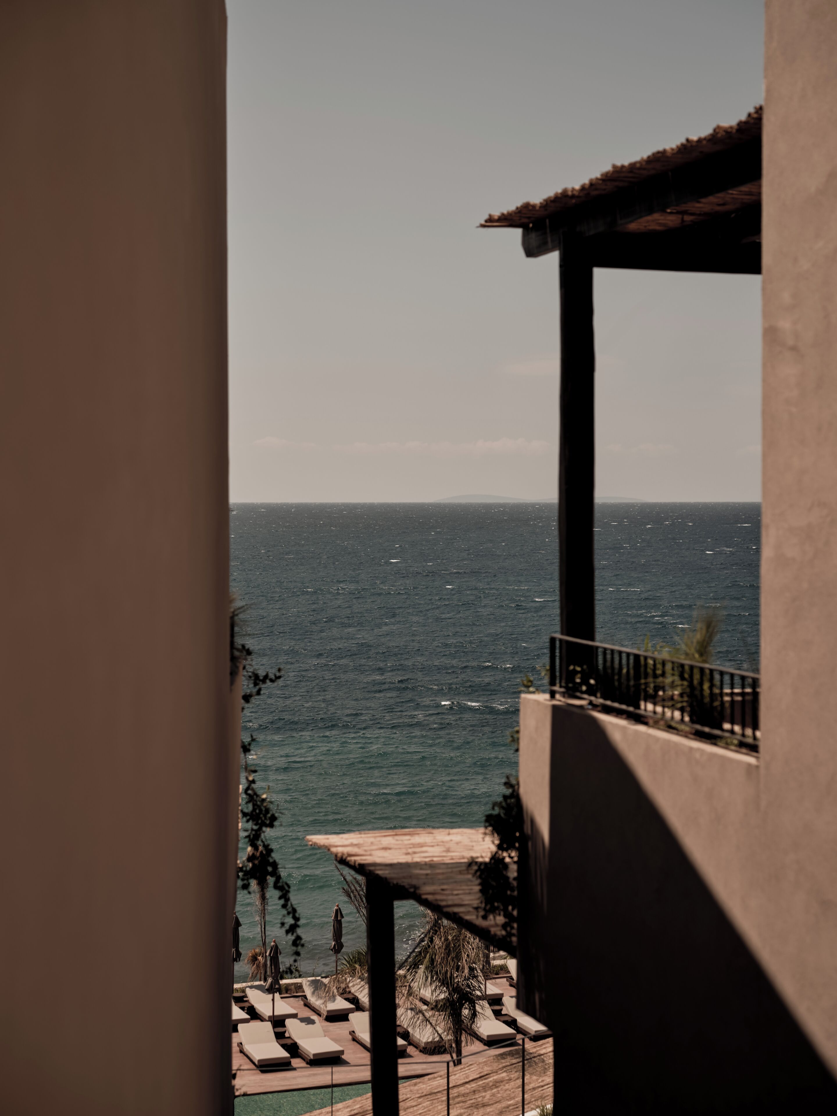 Un balcó amb vista al mar, seients de relaxació i zona de piscina.