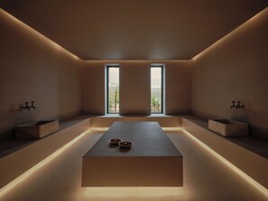 A minimalist bathroom with a central platform, two sinks, and a view of greenery through a window. - Oku Bodrum (Bodrum)