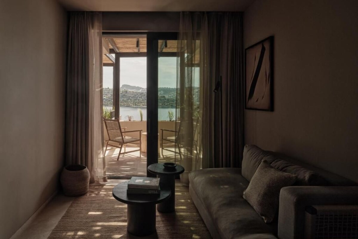 Un salon chaleureux avec un canapé, une table basse et une vue sur un balcon aménagé avec du mobilier d’extérieur.