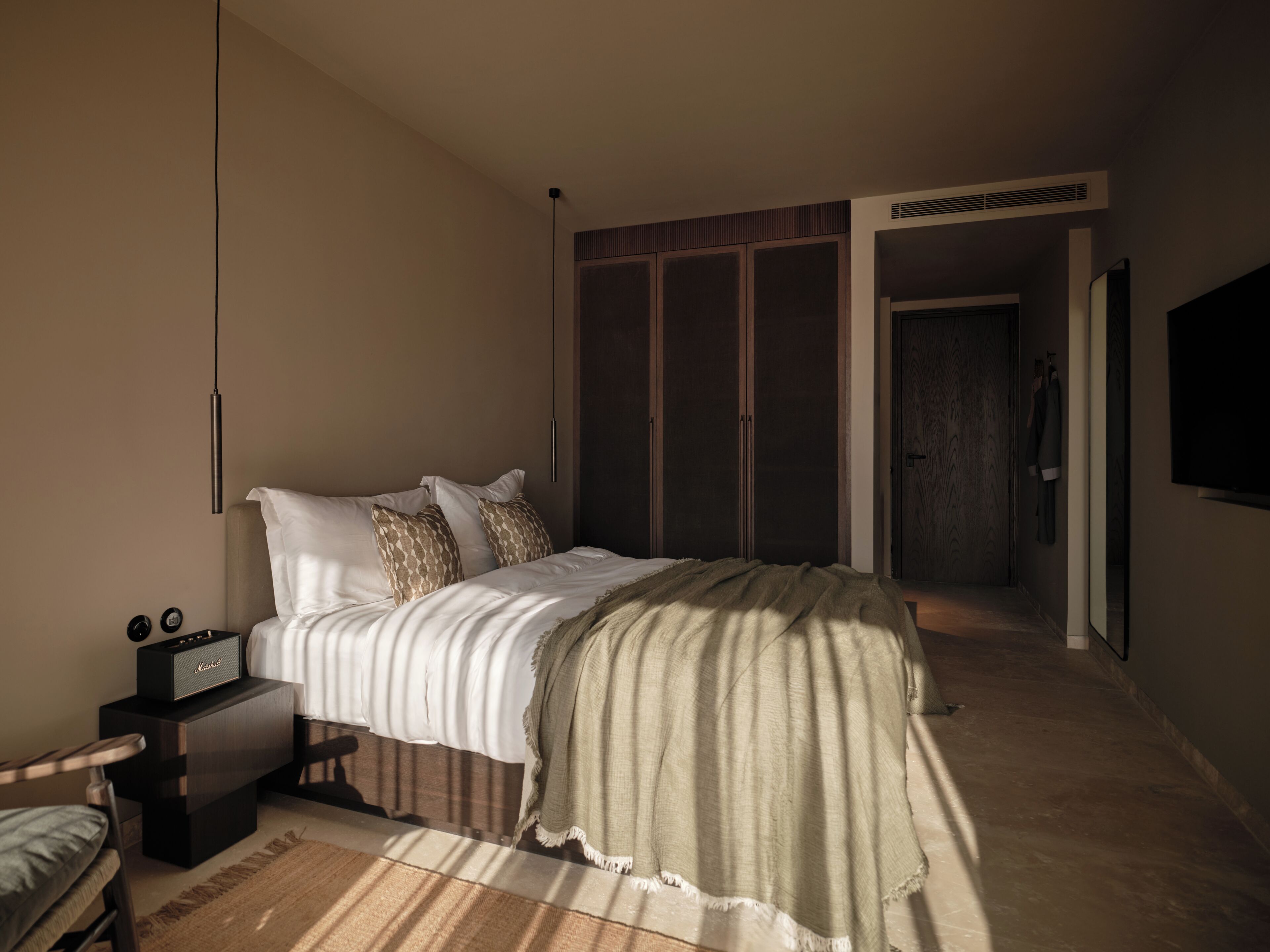 Un dormitorio con cama, mesita de noche, lámpara, armario y televisor.