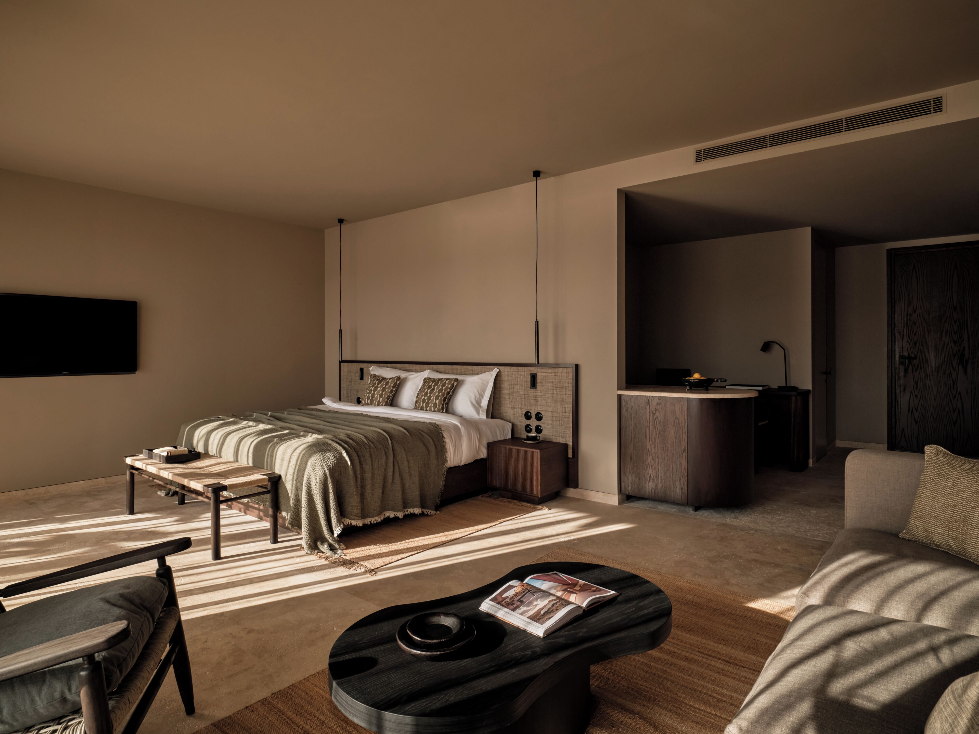 Een moderne slaapkamer met een bed, nachtkastje en een leeshoekje met een tijdschrift.