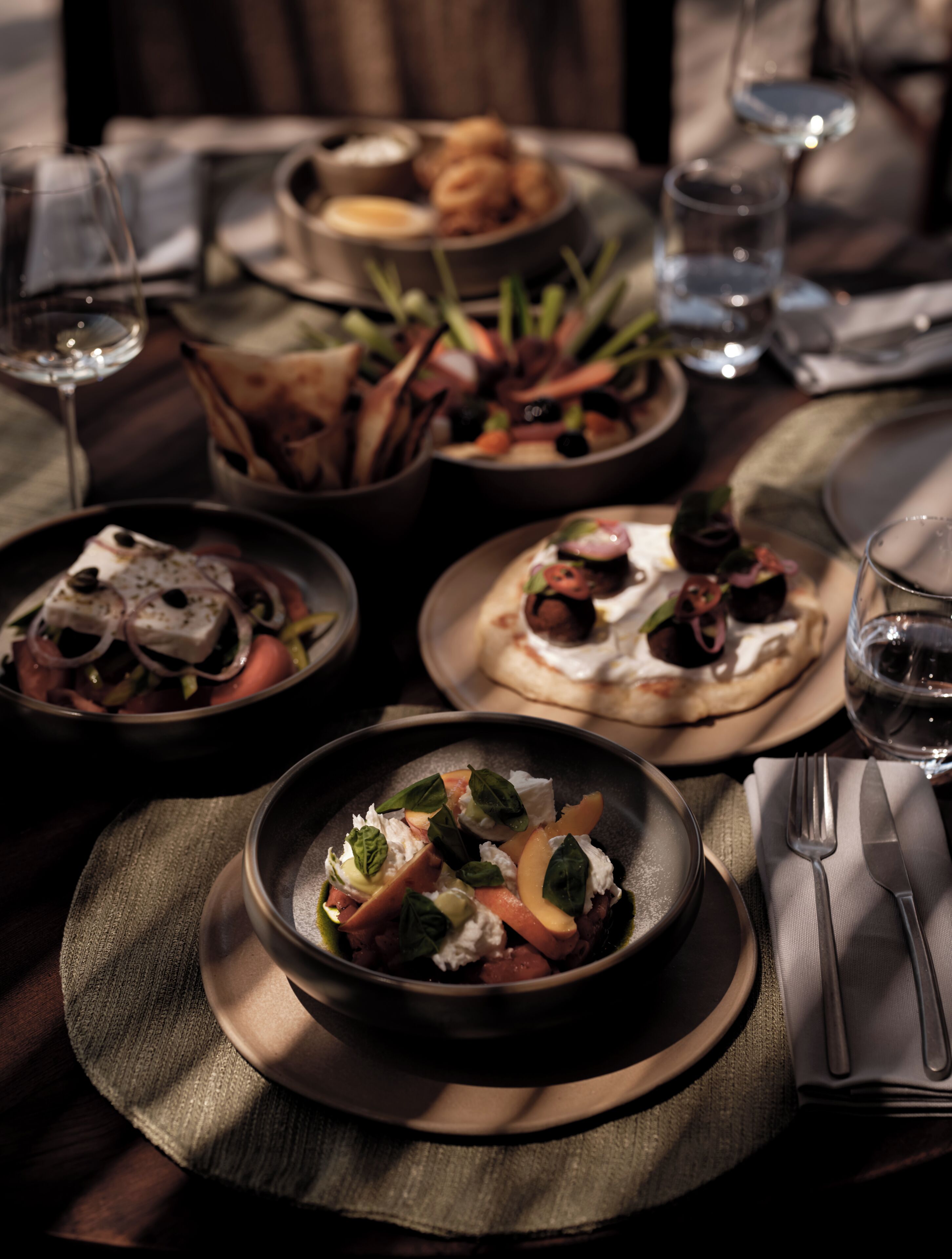 Une table à manger avec différents plats, des verres et des couverts.