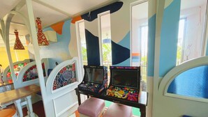 Un área de juegos infantiles con máquinas de videojuegos, asientos y elementos decorativos.