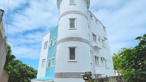 Una torre blanca con un extremo redondeado, múltiples ventanas y un tejado azul.