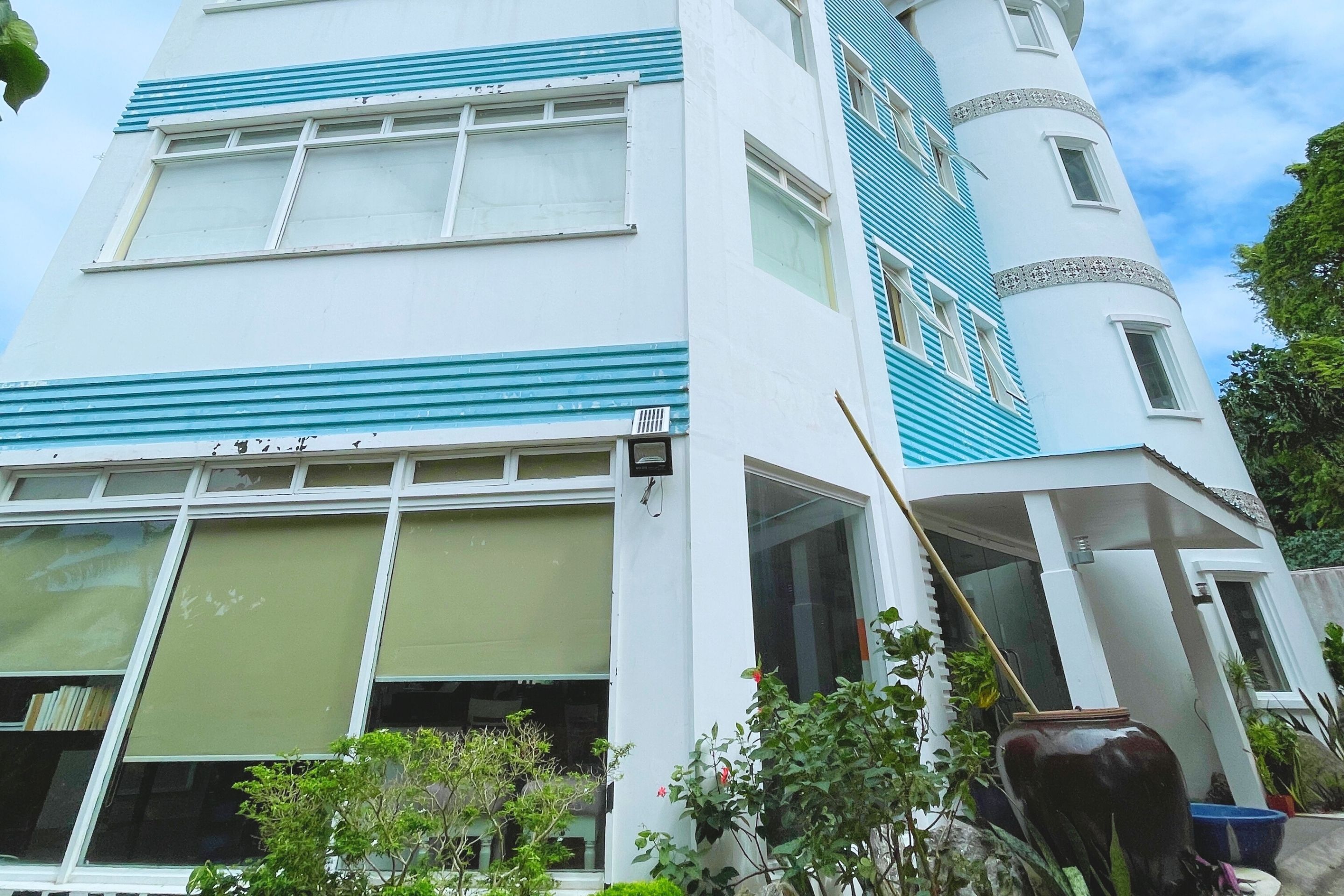 A modern building with a white facade and blue accents, featuring large windows and a cylindrical tower.