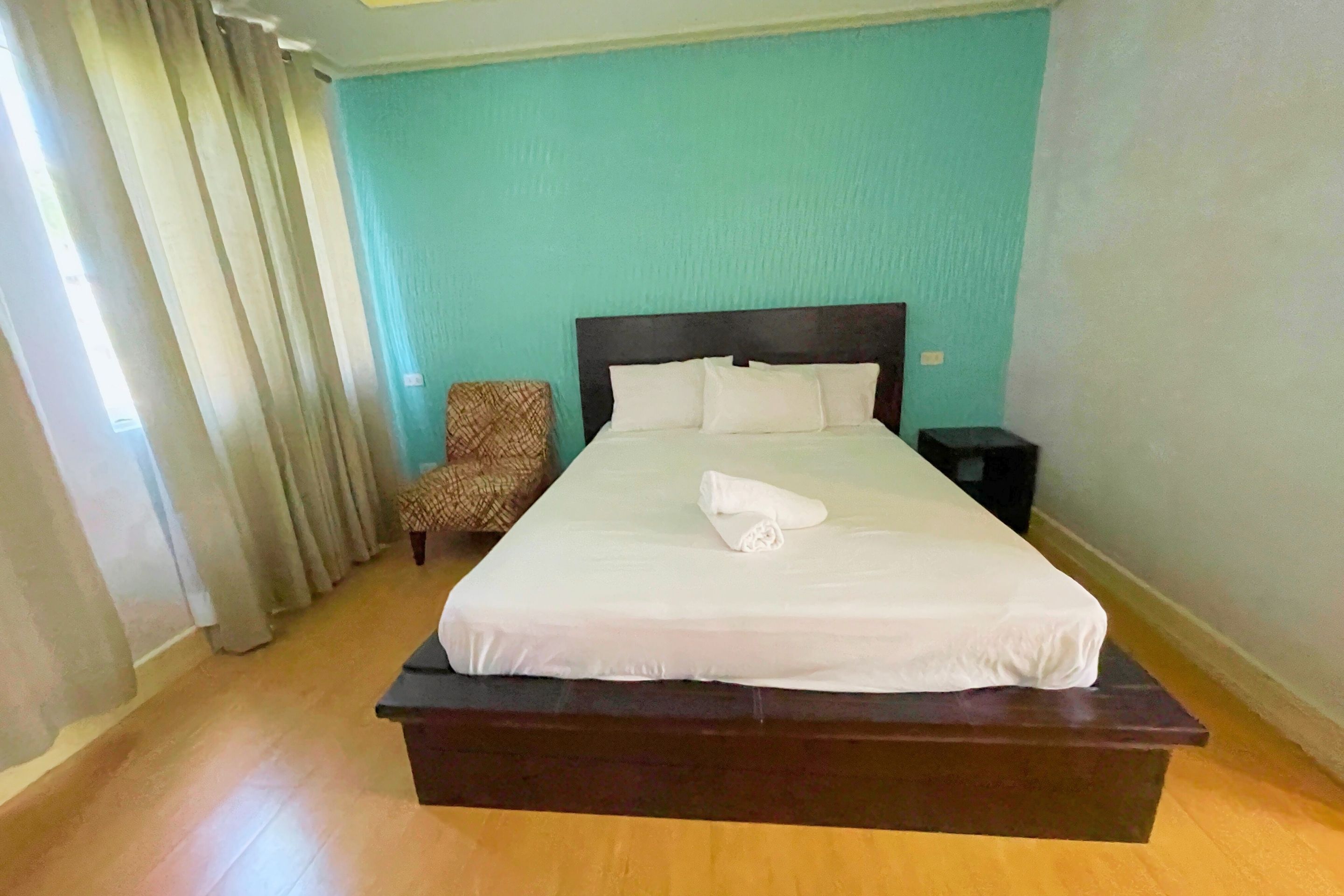A hotel room with a large bed, a chair, and a nightstand.