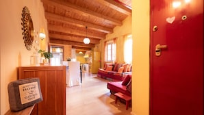 A cozy interior with a wooden ceiling, a red door, and a seating area with a sofa and cushions. - Casa Milla In Center Town (Lucca)