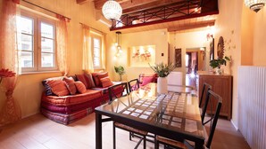 A cozy living room with a glass-top dining table, a sofa with cushions, and a wooden ceiling. - Casa Milla In Center Town (Lucca)