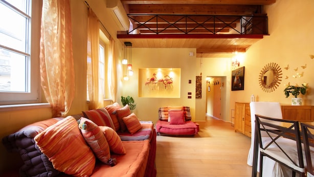 A cozy living room with a sofa set, a dining area, and a staircase leading to an upper level. - Casa Milla In Center Town (Lucca)