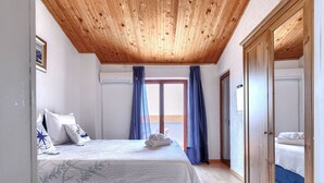 A bedroom with a wooden ceiling, a bed with a blue headboard, a wardrobe, and a window with curtains. - Apartment Meazza by Interhome (Medulin)