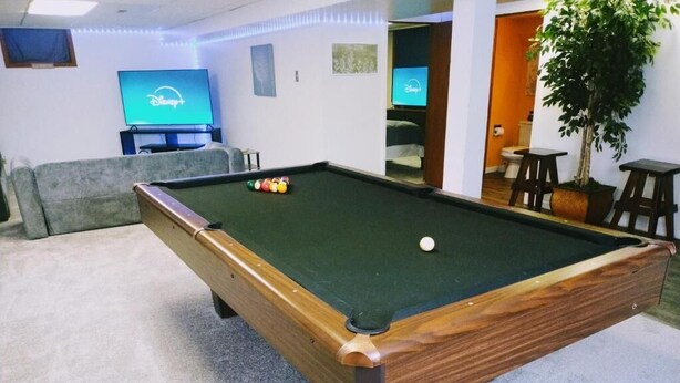 A pool table with a green felt surface, a wooden frame, and a white cue ball. - "Charming Oasis: Sleeps 11: Pool Table: Big screens: Full Kitchen" (Kansas City)