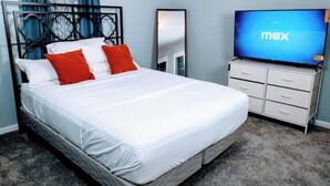 A hotel room with a bed, a TV, a mirror, and a dresser. - "Charming Oasis: Sleeps 11: Pool Table: Big screens: Full Kitchen" (Kansas City)