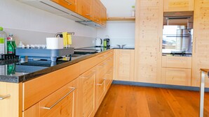 A modern kitchen with wooden cabinets, a stainless steel sink, and a built-in oven. - Kronenplatz 11 OG by Interhome (Lenk)