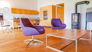 A modern kitchen with wooden cabinets, a dining area with a wooden table and chairs, and a black stove. - Kronenplatz 11 OG by Interhome (Lenk)