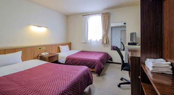 Une chambre d’hôtel avec deux lits, un bureau avec un ordinateur, une chaise, un miroir et une fenêtre avec des rideaux.