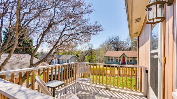 A wooden deck with outdoor furniture, a red door, and a view of neighboring houses. - Cottage Retreat Home (Rossville)