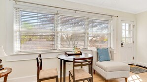 A room with a dining table, two chairs, a sofa, and a window with blinds. - Cottage Retreat Home (Rossville)