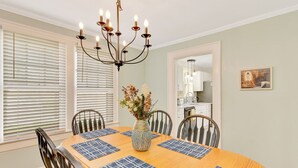 A dining room with a wooden table, blue placemats, a vase with flowers, and a chandelier. - Cottage Retreat Home (Rossville)