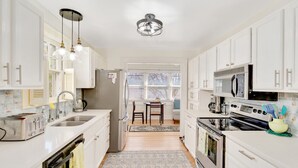 A modern kitchen with white cabinets, stainless steel appliances, and pendant lighting. - Cottage Retreat Home (Rossville)