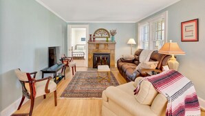 A living room with a fireplace, a sofa, a coffee table, and a television. - Cottage Retreat Home (Rossville)