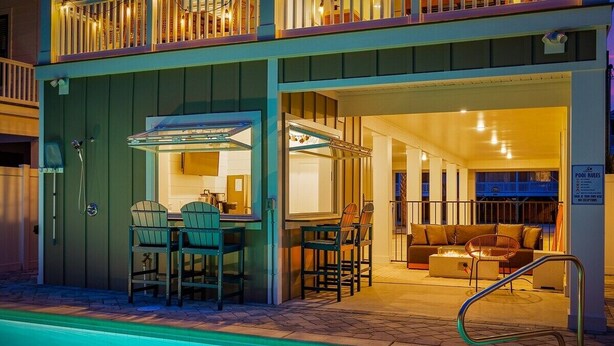 A two-story building with a pool, outdoor seating, and a covered patio area. - Luxury 5BR Escape | Pool & Hot Tub | Sleeps 16 (Surfside Beach)