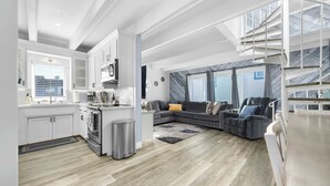 Una cocina moderna con muebles blancos, horno empotrado y un cubo de basura de acero inoxidable.