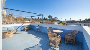 Terraza en la azotea con mobiliario de mimbre, un hogar de piedra y vistas de edificios circundantes.