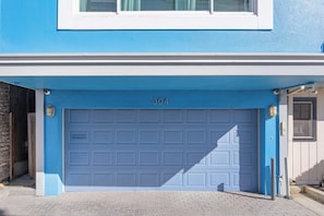 Eine blaue Garagentür mit der Nummer 304, ein Fenster darüber und ein Kopfsteinpflasterweg.