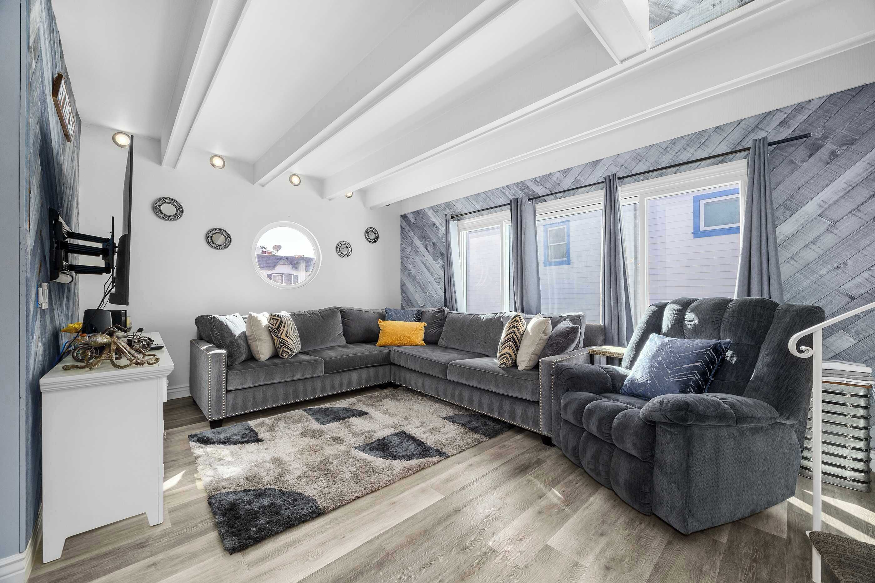 Una sala de estar moderna con un sofá modular, un espejo redondo y vistas al exterior.