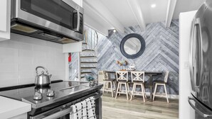 A modern kitchen with a stainless steel range, a kettle, and a herringbone-patterned backsplash.