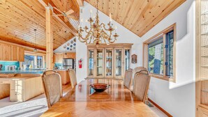 A spacious dining area with a large wooden table, surrounded by wicker chairs, and a central chandelier.