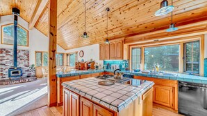 A spacious kitchen with wooden cabinets, a large island, and a brick fireplace.