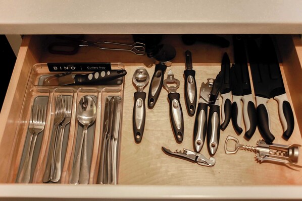 A drawer containing various kitchen utensils including spoons, forks, knives, and a bottle opener. - Sojourn at Colley Manor Unit 4 (Norfolk)