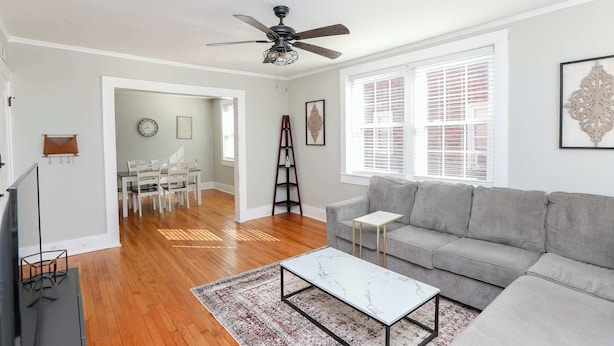 A living room with a grey sofa, a white coffee table, a ceiling fan, and a dining area with a white table and chairs. - Sojourn at Colley Manor Steps from Local Favorites Unit #6 (Norfolk)