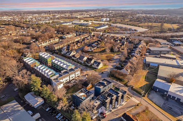 An aerial view of a residential area with houses, a parking lot, and a large building with a flat roof.