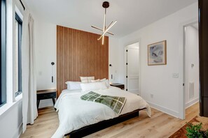 King bedroom with wood accent wall and pendant light gives couples their own retreat while the party happens downstairs