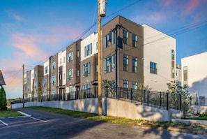 A multi-story residential building with a modern design, featuring a mix of brown and white exteriors, large windows, and a black metal fence surrounding the property. - Nashville-themed rooftop bar retreat, sleeps 12 near Geodis Park (Nashville)