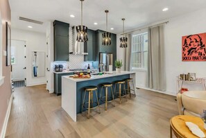 A modern kitchen with a central island, bar stools, pendant lighting, and a large window. - Nashville-themed house with rooftop bar & game room, sleeps 12 near Geodis Park (Nashville)